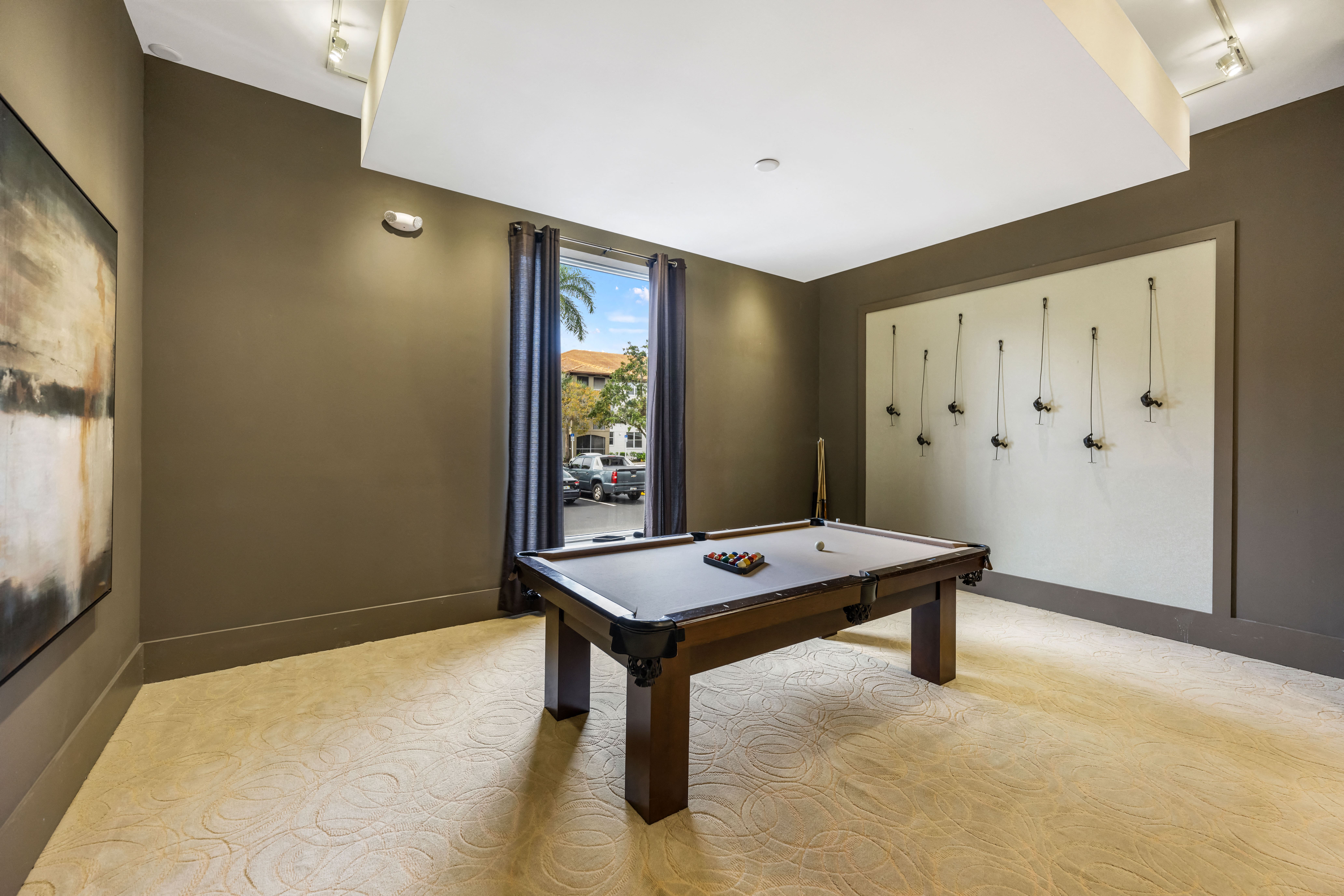 A pool table in a room with brown walls and a window.
